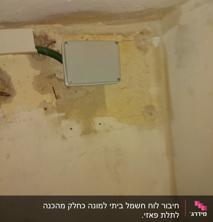 קופסת חיבורים חשמלית עם כבל ירוק בקיר